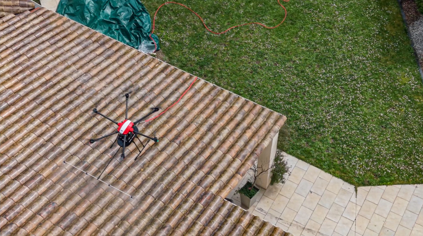 Vue d'un drone entrain de pulvériser sur un toit. La photographie est prise 3/4 haut de dessus